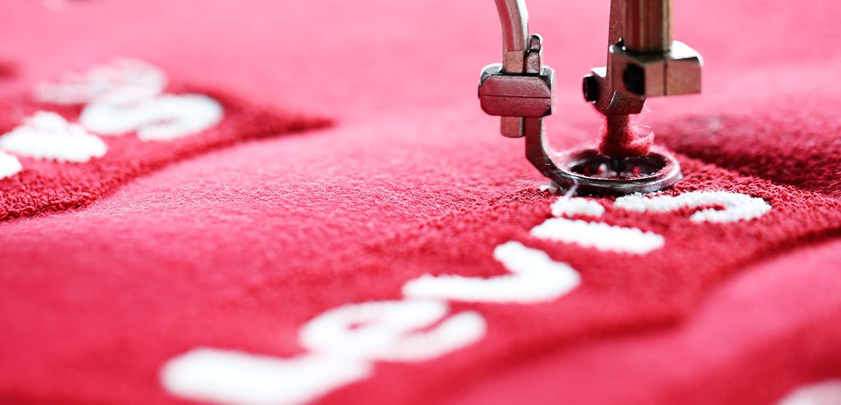 embroidery sewing machine close-up on red fabric with logo stitching